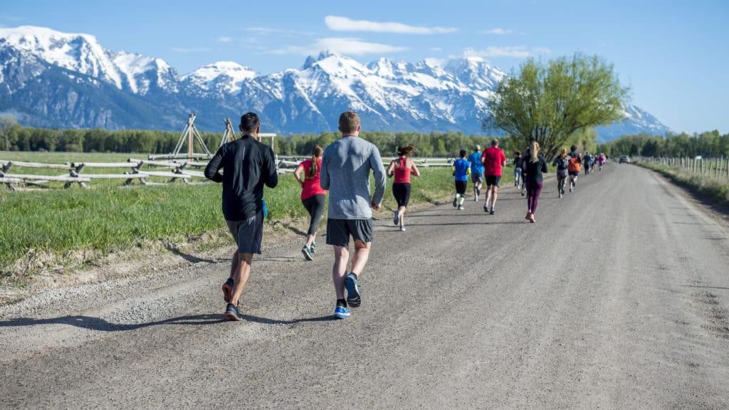 Runners on path with snowy teton mountains in the background