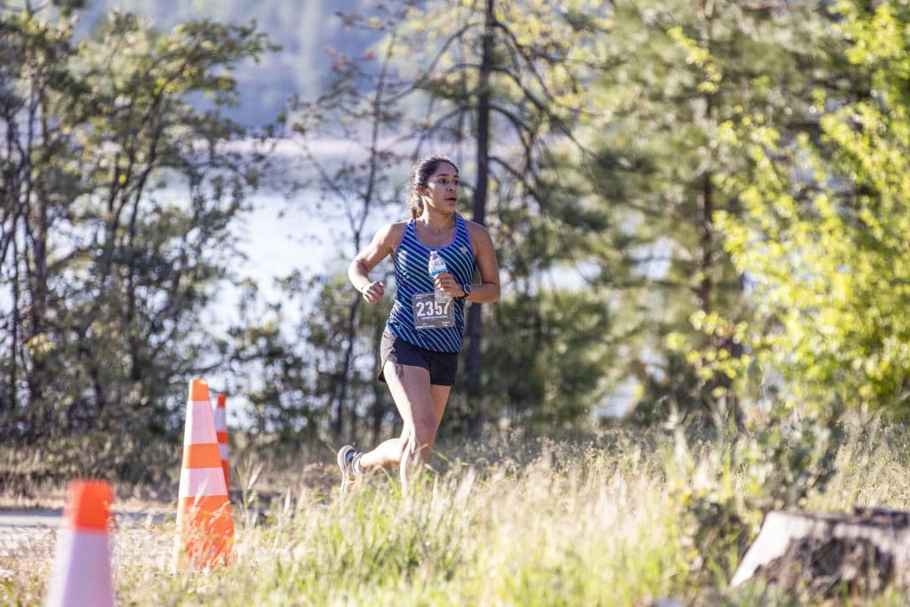 A runner coming over a hill with trees around her