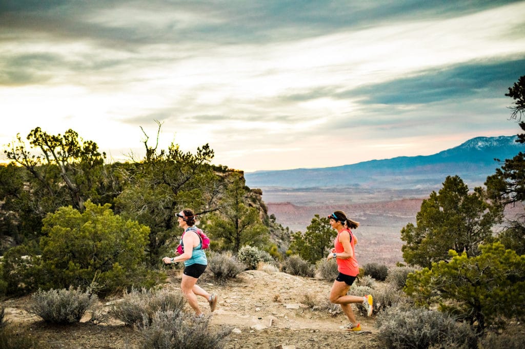 two women running with sunset behind them