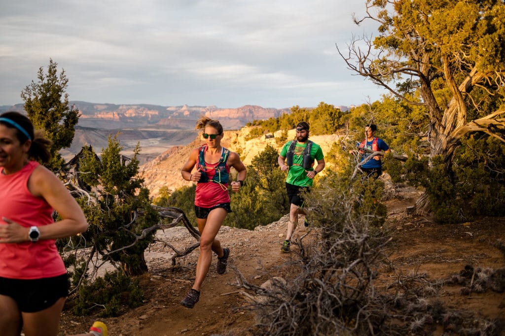 group of runners sprinting next to a cliff