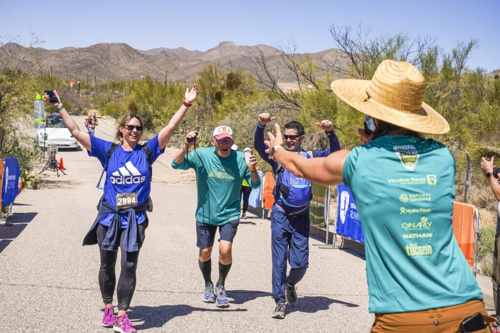 three runners crossing the finish line with arms raised