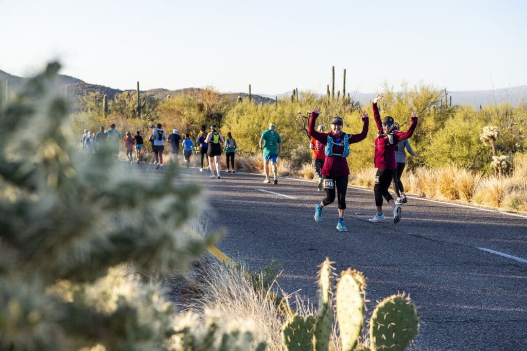 two runners on paved road turning to pose for the camera