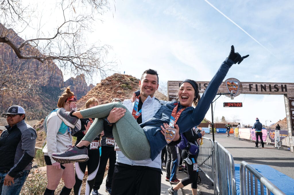 A man holding a woman and posing at the finish line