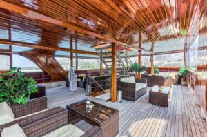 A lower deck of the yacht with table and cushioned chairs in the shade