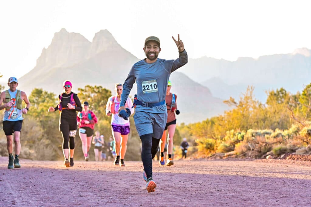 A group of people running with the front person holding up a peace sign