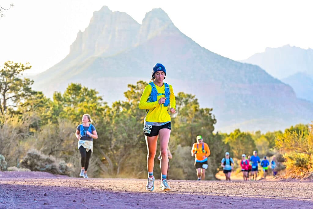 A group of people running towards the camera with a mountain peak behind them