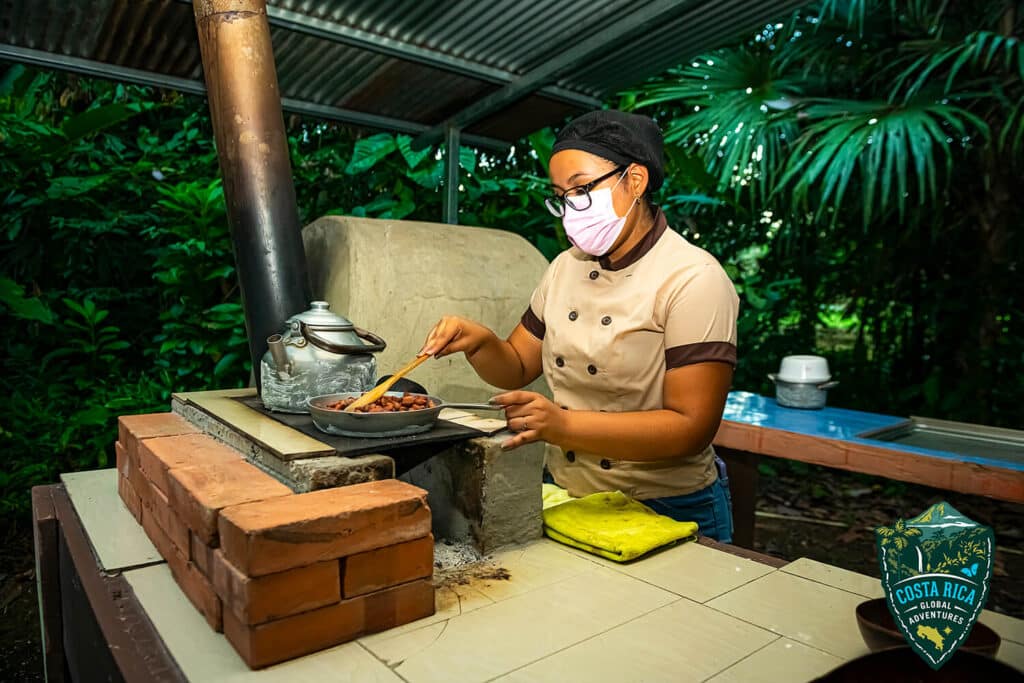 A young woman roasting cocoa beans on a small brick stove