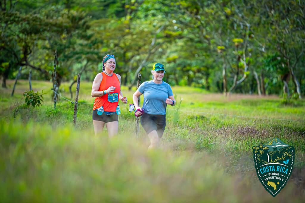 Two runners in  a field of brush coming over a hill