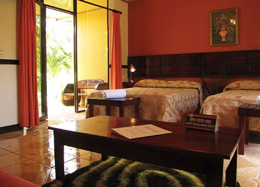 A red hotel room with two beds and a rear patio