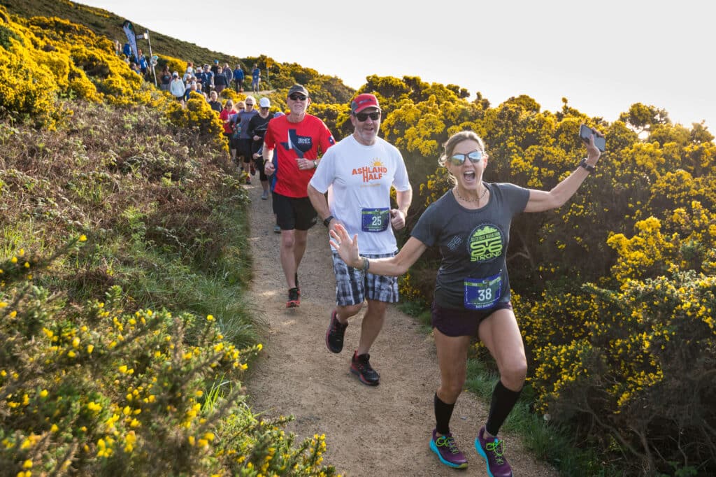 line of runners approaching the camera as they descend a flower covered hill