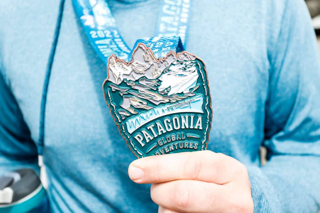 a hand holding a Patagonia Global Adventure medal