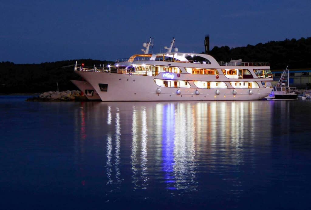 Melody yacht at night with lights shining on still water