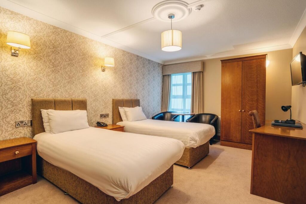 warmly lit hotel room with two twin beds