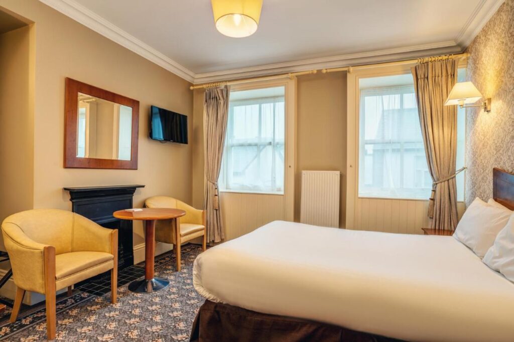 A brightly lit hotel room with two yellow armchairs