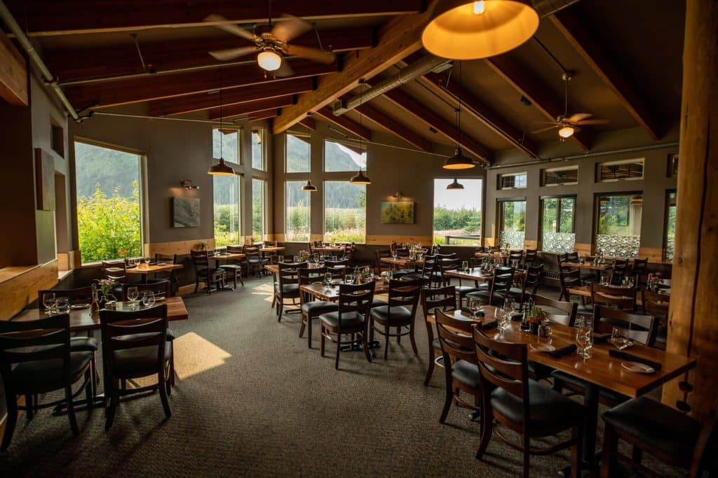 A pine ceiling covers a well-lit, warm dining room full of wooden tables and chairs