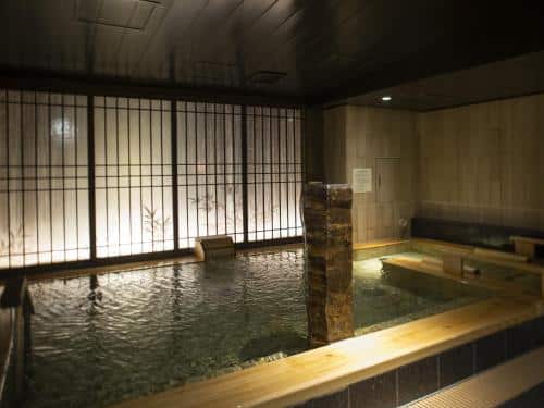 An indoor onsen with stone features and low lit ambiance