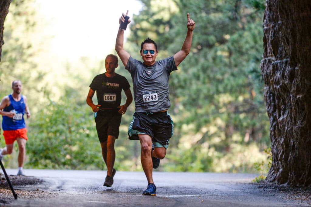 Vacation Races runner lifting their arms with pride as they pass through the on course tunnel