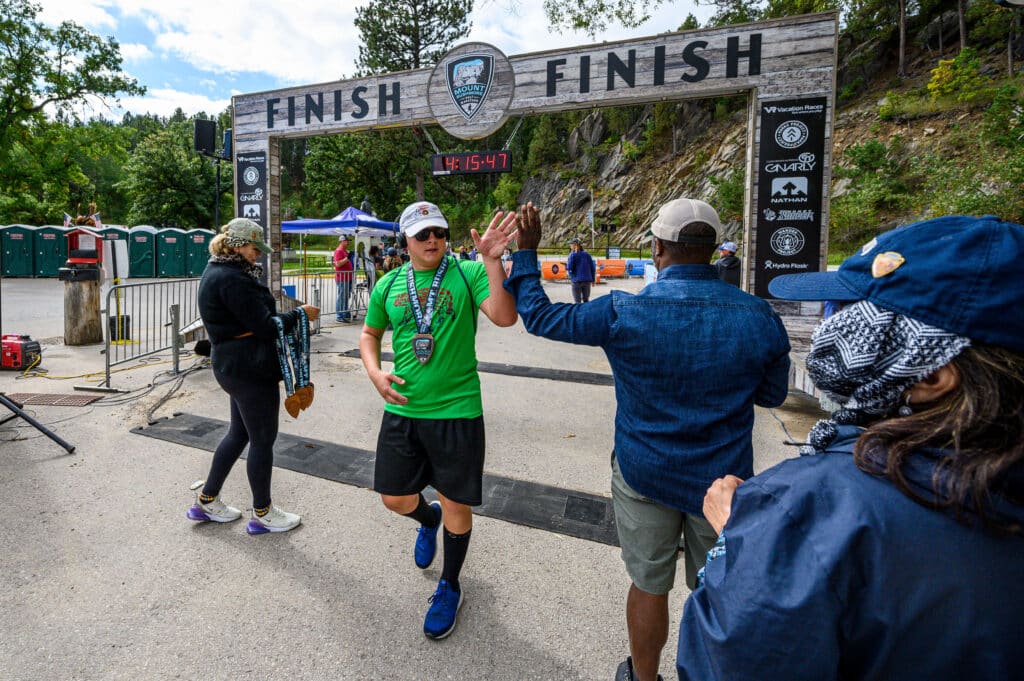 Vacation Races Half Marathon runner crossing the finish line with a high five at Mount Rushmore