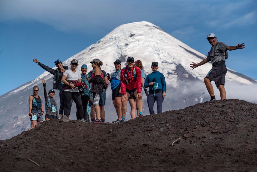 A group of Vacation races runners stand celebrate their running trip framed by Osorno Volcano in Peulla, Chile