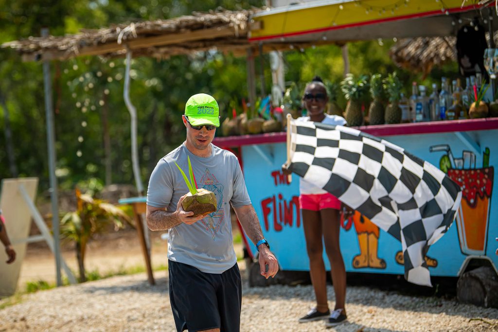 A runner drinks from a coconut as they pass a pit stop on their tropical run