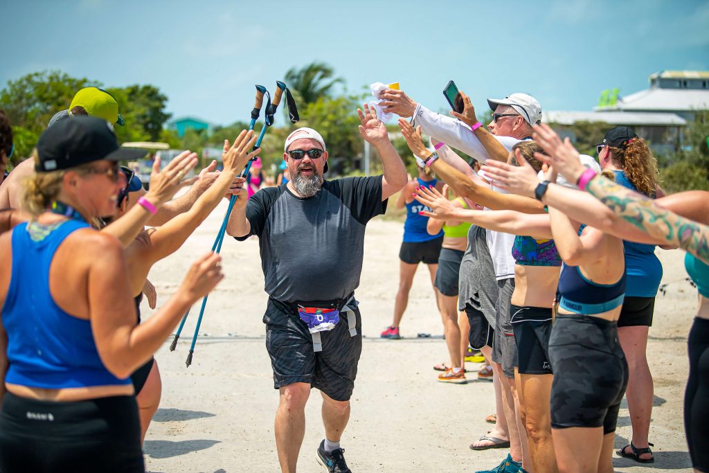 Runners high five a runner as he crosses the finish line at the Belize Global Adventure