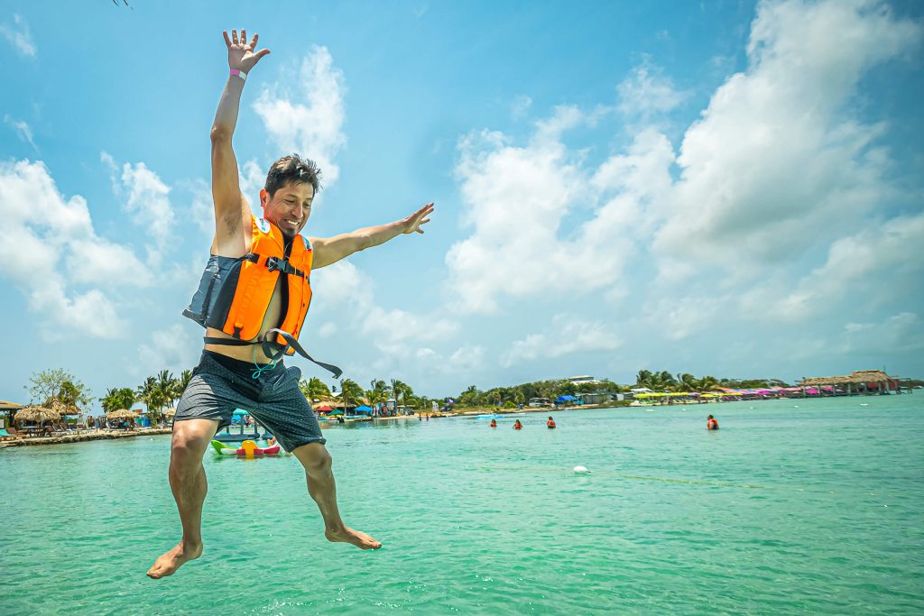 A runner in a neon life vest jumps into crystal clear waters in San Pedro