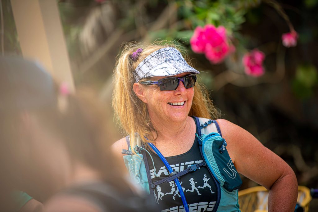 A Global Adventures by Vacation Races runner smiles through sunglasses as she waits to start her daily trail run