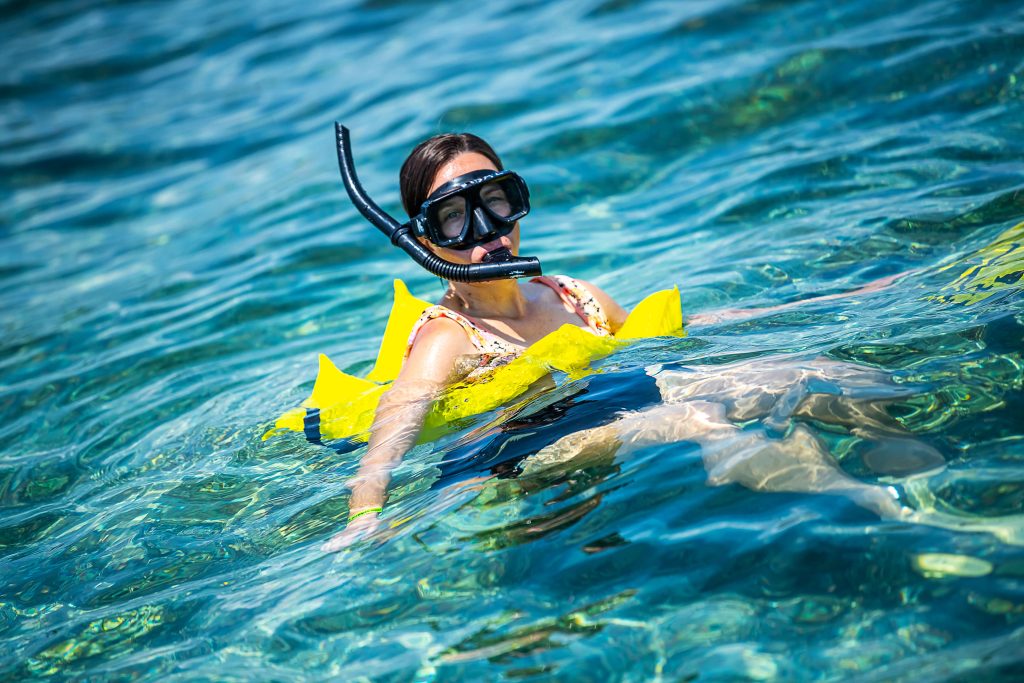 Glistening water surrounds a runner snorkeling on Ambergris Caye in Belize