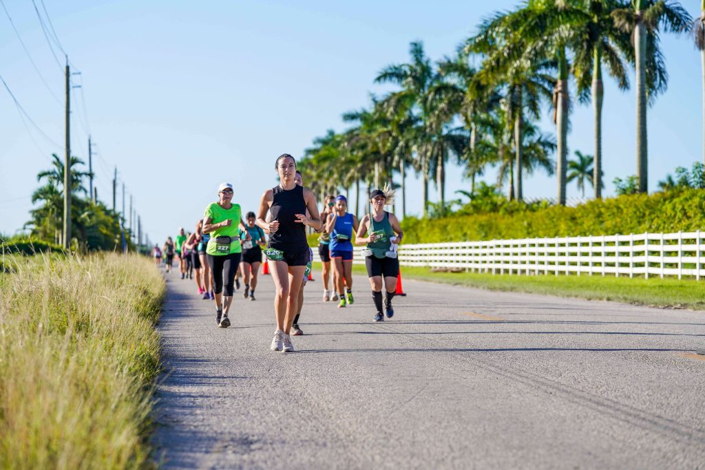 A group of runners head down the Everglades Half Marathon course with the sun on their back and palm trees waving in the breeze