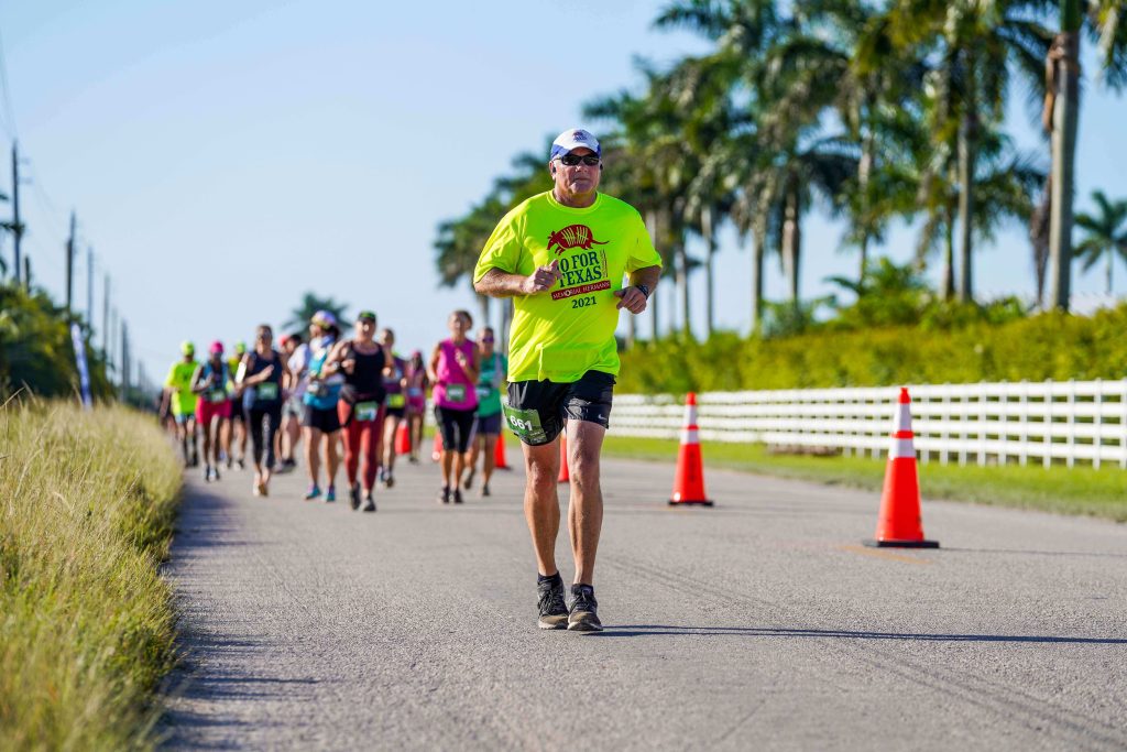 A runner in a neon shirt strides along on the Everglades Half Marathon course