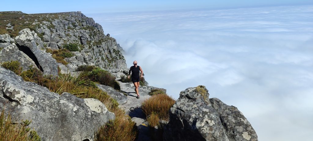 A woman running a stone trail against clouds on Table Mountain in South Africa