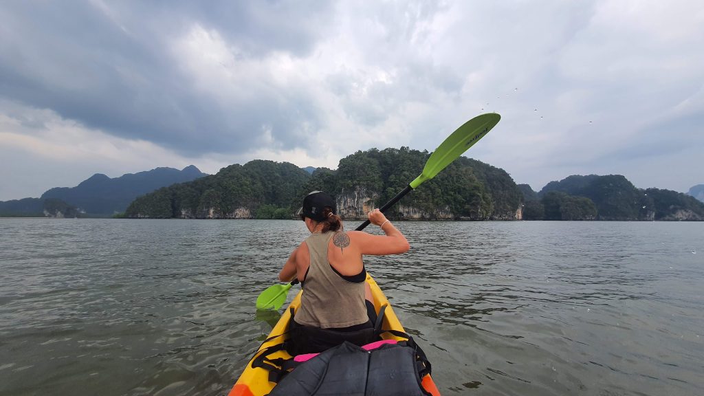 A woman kayaks in the waters of Thailand on he running vacation