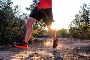 A runner passes by atop Gooseberry Mesa with the sun shining on him at the Vacation Races Zion Ultra
