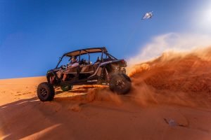 An ATV flies overhead kicking up sand on the dunes of Sand Hollow