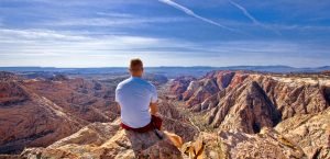 A solo hiker contemplates the vast sandstone rolling landscape of Snow Canyon in Greater Zion